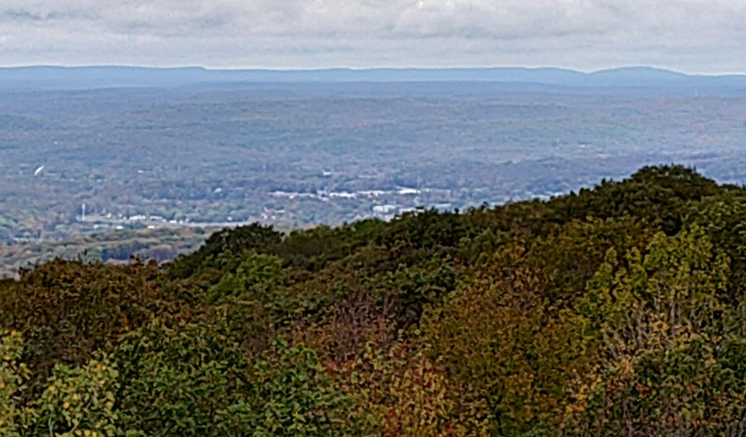 The view north from the Fox Gap transmitter site: a forested ridge in the foreground, the Stroudsburg valley beyond it, and a distant ridgeline on the horizon.